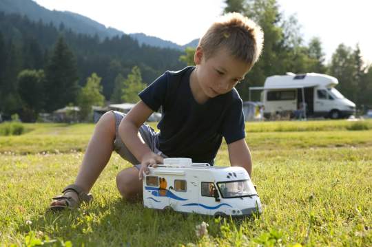 Boy playing with toy RV in front of family RV